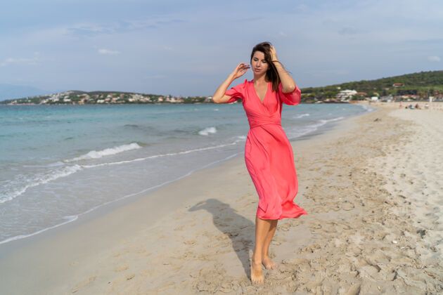快乐夏日快乐性感的女人穿着华丽的粉色连衣裙在沙滩上摆姿势全长女孩海滩女性