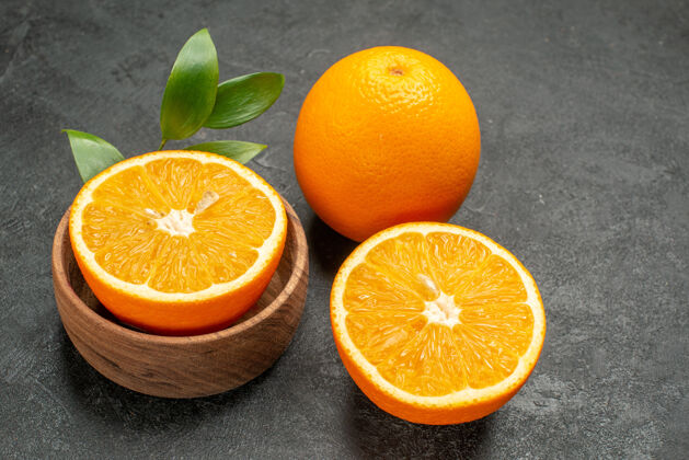 健康在黑暗的桌子上 近距离观看整个切下的带叶子的新鲜橙子封闭可食用水果柑橘