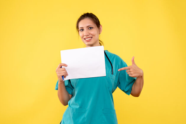 微笑正面图黄色背景下穿着医疗衫的女医生拿着纸分析纸病毒黄色
