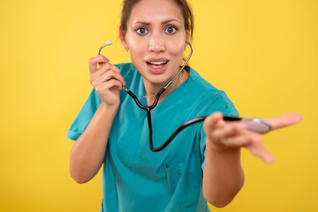 正面正面图黄色背景 穿着医用衬衫 带听诊器的女医生病毒护士医生