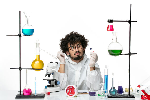 实验室正面图身着特殊套装的年轻男科学家拿着样品站在白墙上套装科学样品