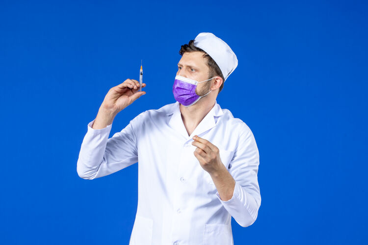 外套男医生的前视图 穿着医疗服 戴着蓝色的疫苗注射面罩实验室外套套装大流行