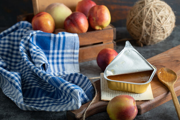 打开桃子和木勺放在木板上的甜果酱果冻生的压缩