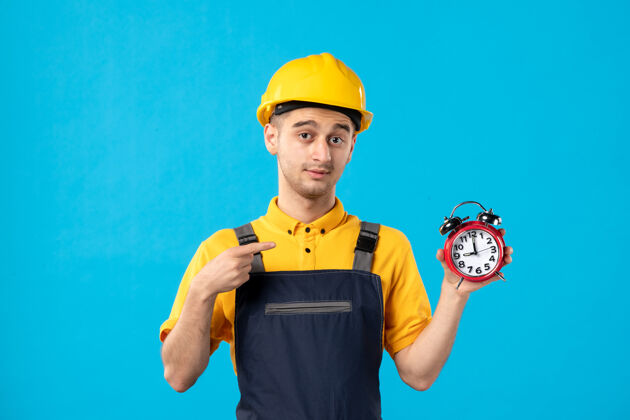 建设者穿着制服的男工人正对着蓝色的时钟施工承包商指点