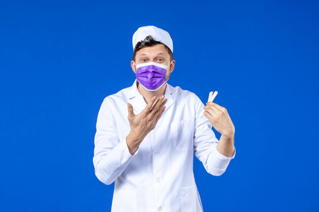 男医生前视图中的男医生穿着医疗服和面具举行小医疗补丁蓝色病毒套装疫苗