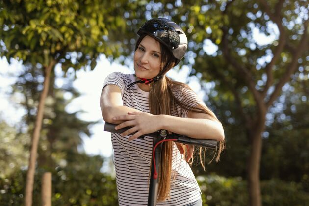 科技一个年轻女子在公园里骑着电动滑板车快速城市车轮