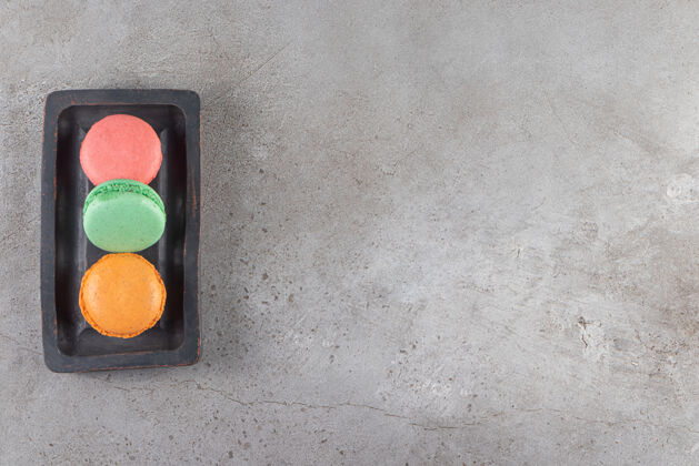 甜点不同颜色的通心粉饼干放在深色的木板上开心果蛋糕通心粉