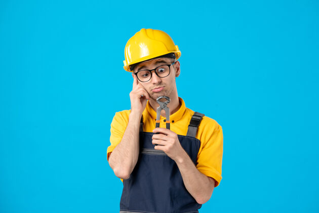 服务穿着黄色制服的男工人的正视图 钳子在蓝色上工程师工作男工人