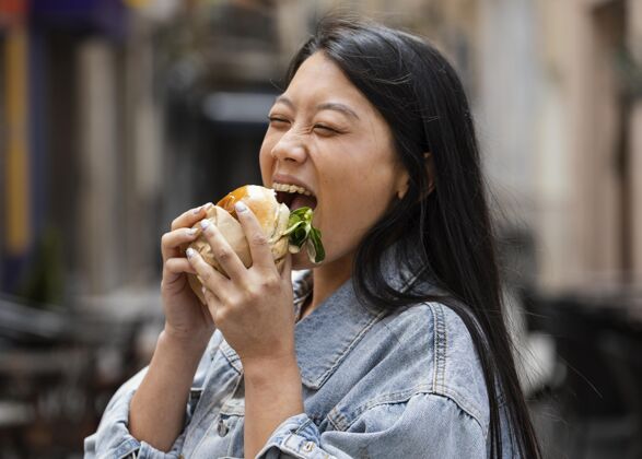 都市快乐的亚洲女人在户外吃汉堡街头食品美味顾客