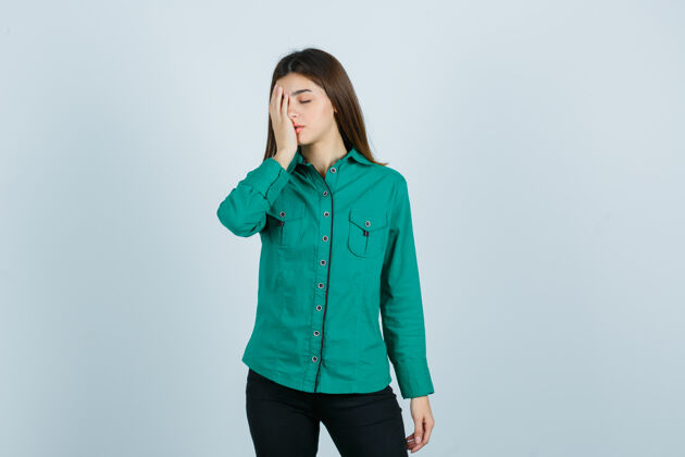 成人照片中的年轻女性手拉手 穿着绿色衬衫 裤子 看上去很疲惫疼痛沮丧沮丧