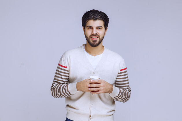 服装一个穿着白衬衫的男人拿着一杯咖啡聪明成人人类