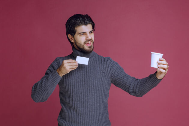 年轻拿着咖啡杯展示账单或名片的男人休息男性顾客