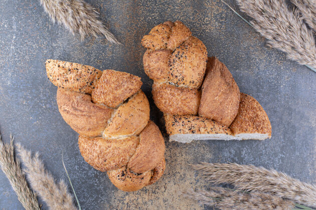 切片切成两半的斯特拉西亚面包和一捆麦秆放在大理石表面面包外套小麦