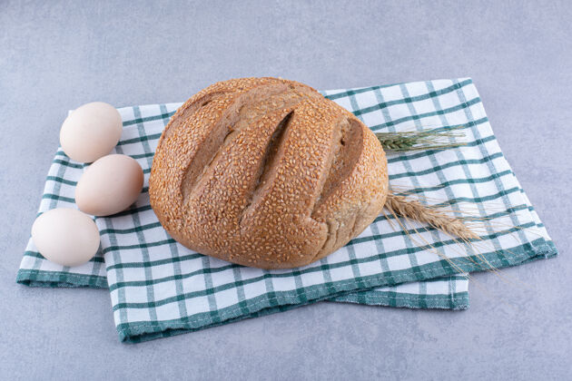 农产品鸡蛋 面包 麦秆放在折叠毛巾上的大理石表面早餐配料面团