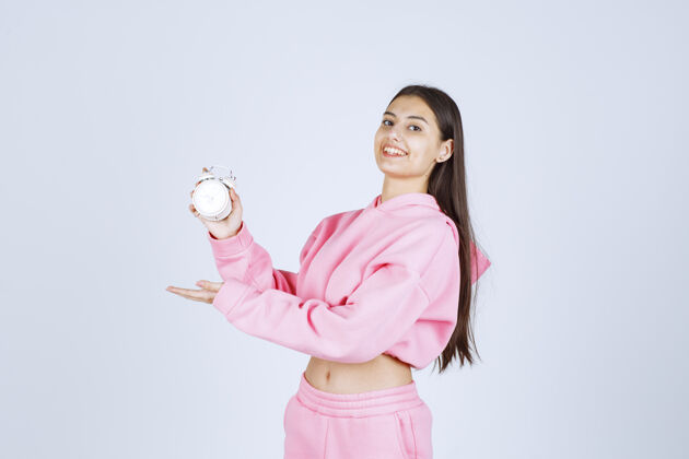 员工一个穿着粉色睡衣的女孩拿着一个闹钟 把它当作一个产品来推销模特表演销售