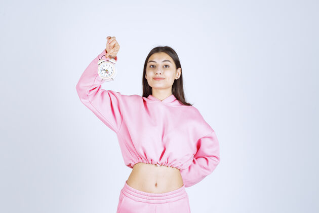 销售一个穿着粉色睡衣的女孩拿着一个闹钟 把它当作一个产品来推销工人雇员年轻