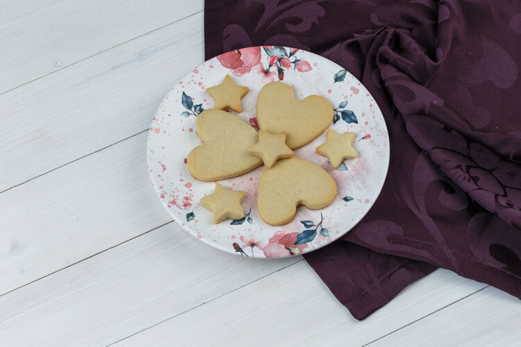 糖一些饼干放在木制和纺织背景的盘子里 高角度观看盘子面包屑脆