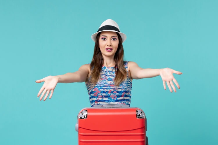 封面女郎前景色美丽的女性准备度假与她的红色袋子上的蓝色空间包美女前面