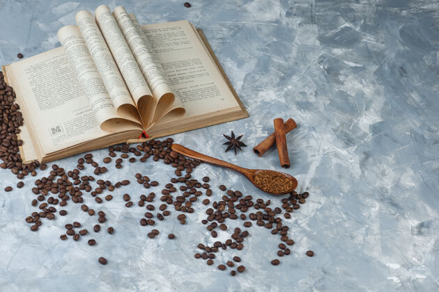 马克杯一些速溶咖啡与书 肉桂在一个木汤匙浅蓝色大理石背景 特写咖啡早晨泡沫