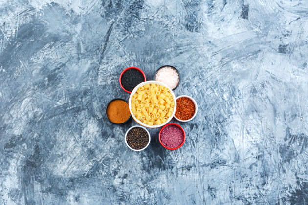 传统在灰色灰泥背景上的碗里放一些带各种香料的意大利面 顶视图膳食奶酪烹饪