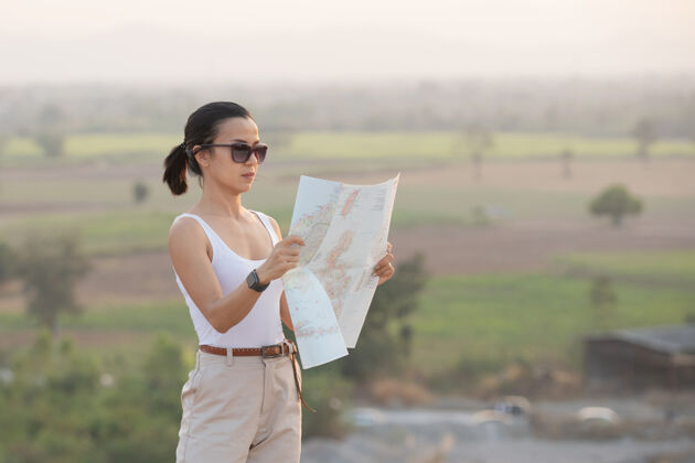 风景一个爱冒险的女孩带着地形图在美丽的山中航行徒步旅行者活动方向