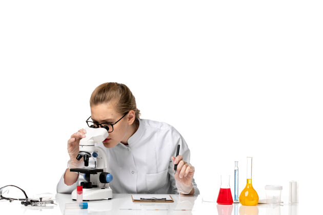 儿童前视图穿着白色医疗服的女医生在白色空间使用显微镜使用疾病病毒