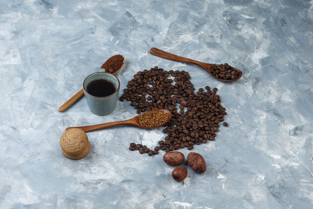 杯子咖啡豆 一杯速溶咖啡 咖啡粉 咖啡豆在木制勺子 曲奇饼高角度查看浅蓝色大理石背景意式浓缩咖啡杯子勺子
