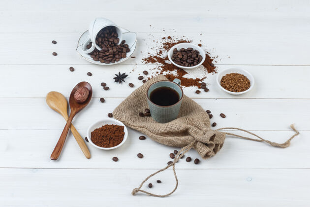 早餐一套咖啡豆 磨碎咖啡 木制勺子和咖啡在一个杯子上的木袋背景高角度的视角厨房新鲜的勺子