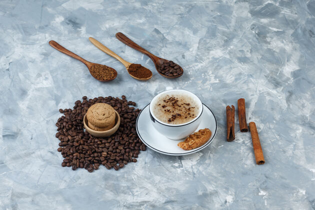 豆子一套饼干 咖啡豆 磨碎的咖啡 肉桂棒和咖啡在一个肮脏的灰色背景杯高角度视图马克杯咖啡套装