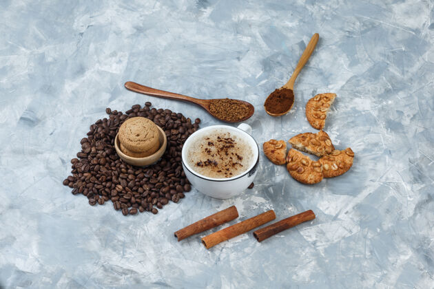 肉桂一套饼干 咖啡豆 磨碎的咖啡 肉桂棒和咖啡在一个肮脏的灰色背景杯高角度视图豆子热的拿铁