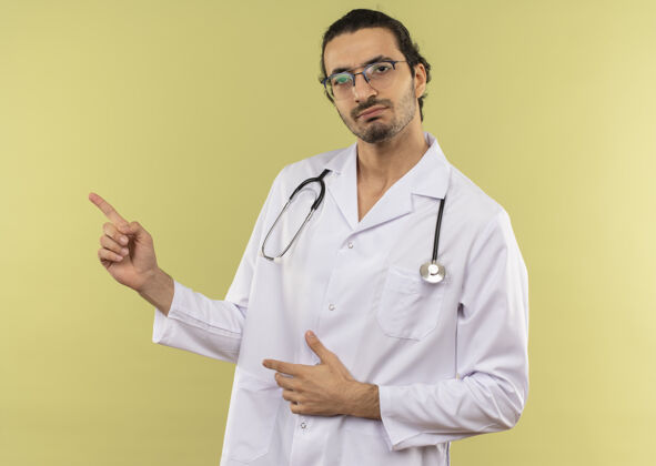 点年轻的男医生戴着眼镜 穿着白袍 用听诊器指着旁边光学男性绿色