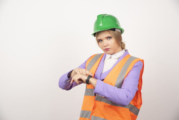 金发女员工指着白墙上的时间安全帽头盔工人