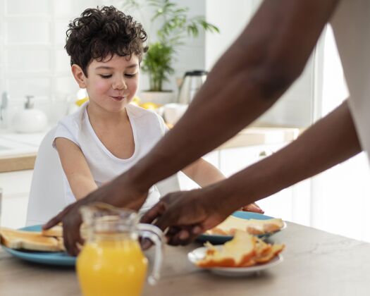 家庭早餐可爱的微笑男孩和他爸爸一起吃早餐食物在一起优质时间