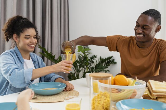 微笑快乐的黑人家庭夫妇喝果汁餐桌快乐的人人