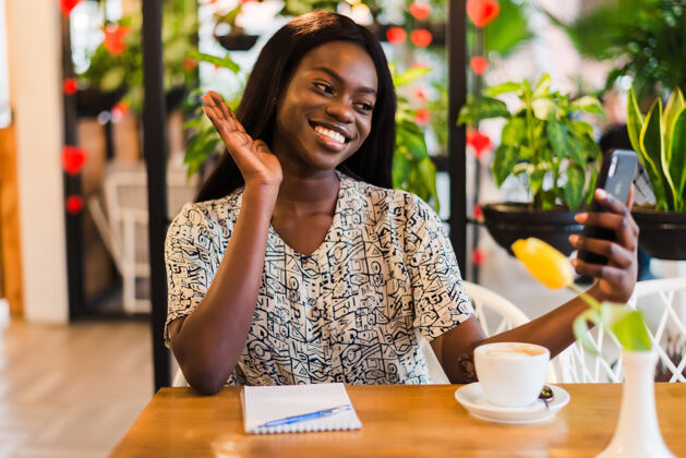微笑年轻的非洲女人在咖啡馆自拍自拍杯子男人
