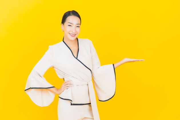 行政美丽的亚洲年轻商业女性在黄色墙上穿着白色西装微笑的画像公司女性朋友
