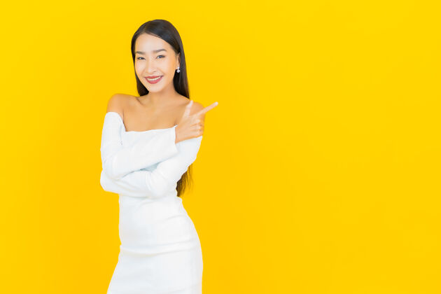 微笑美丽的亚洲年轻商业女性在黄色墙壁上穿着白色裙子微笑的画像亚洲人成人事业