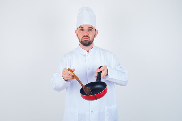 制服年轻的男厨师手拿着空煎锅和木勺 身穿白色制服 俯视前方男厨师薯条
