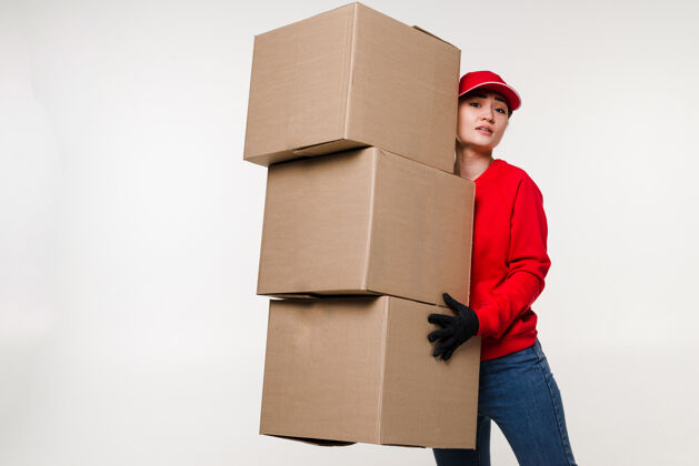 房子送货亚洲女人穿着红色制服隔离在白墙上女人戴帽子t恤牛仔裤作为快递员或经销商拿着纸板箱送货员处理快递