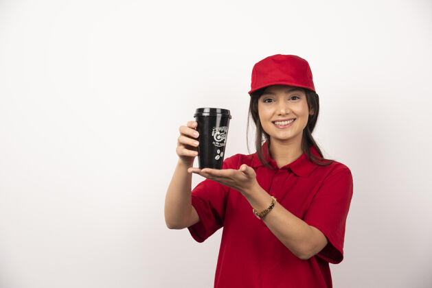 人穿着红色制服的女人在白色背景上展示一杯咖啡年轻人手持肖像