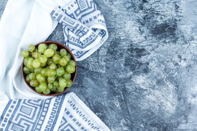 美味绿色的葡萄放在一个粘土碗里 背景是脏兮兮的灰泥和厨房毛巾有机健康串