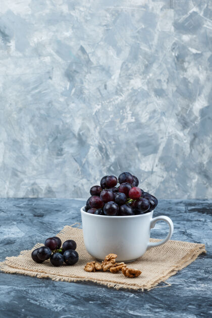 藤蔓一些黑葡萄和胡桃在一个白色的杯子上咕噜咕噜和一块布袋背景 侧视图葡萄葡萄藤健康