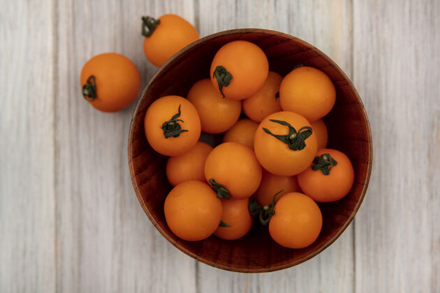 农业新鲜的橙色樱桃西红柿在一个灰色的木制表面木碗顶视图饮食健康美味