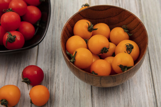 有机有机橙色西红柿在木碗上的顶视图 红色西红柿在灰色木表面的黑色碗上美味食品蔬菜