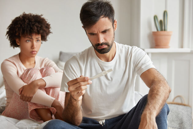 丈夫避孕失败和意外怀孕的概念沮丧的年轻夫妇检查怀孕测试公寓房子生活