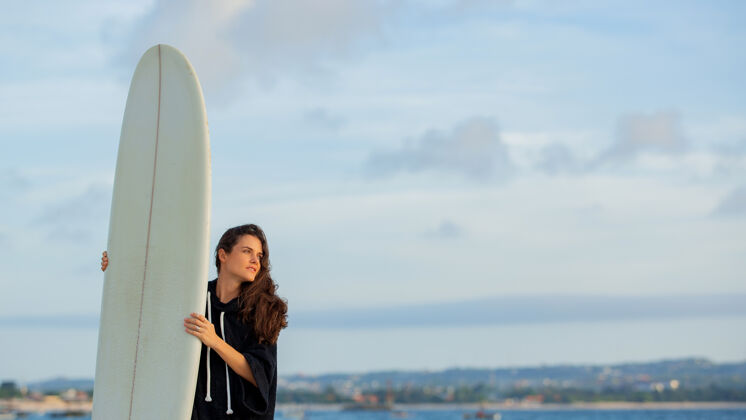 海洋美丽的女孩拿着冲浪板站在沙滩上人海洋女人