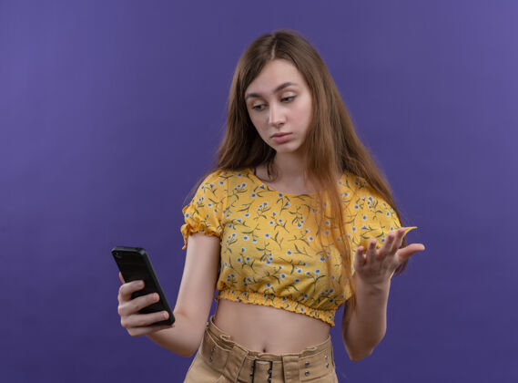 年轻一个体贴的年轻女孩拿着手机 看着孤零零的紫色墙上的手机想女孩拿着