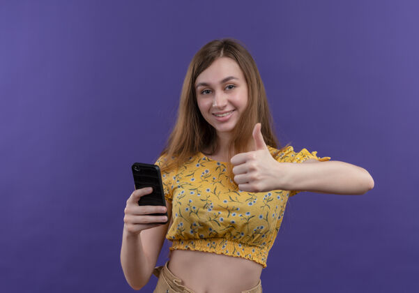 表演微笑的年轻女孩拿着手机 在有复印空间的紫色隔离墙上竖起大拇指女孩电话握着