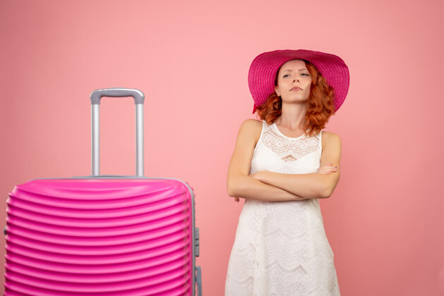 情感年轻的女性游客与粉红色的帽子和粉红色的墙壁上的包的正面视图帽子可爱人