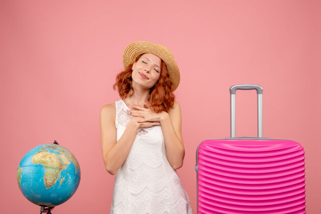 旅行年轻女性游客的正面图 粉红色的墙上挂着粉红色的包航行人头发